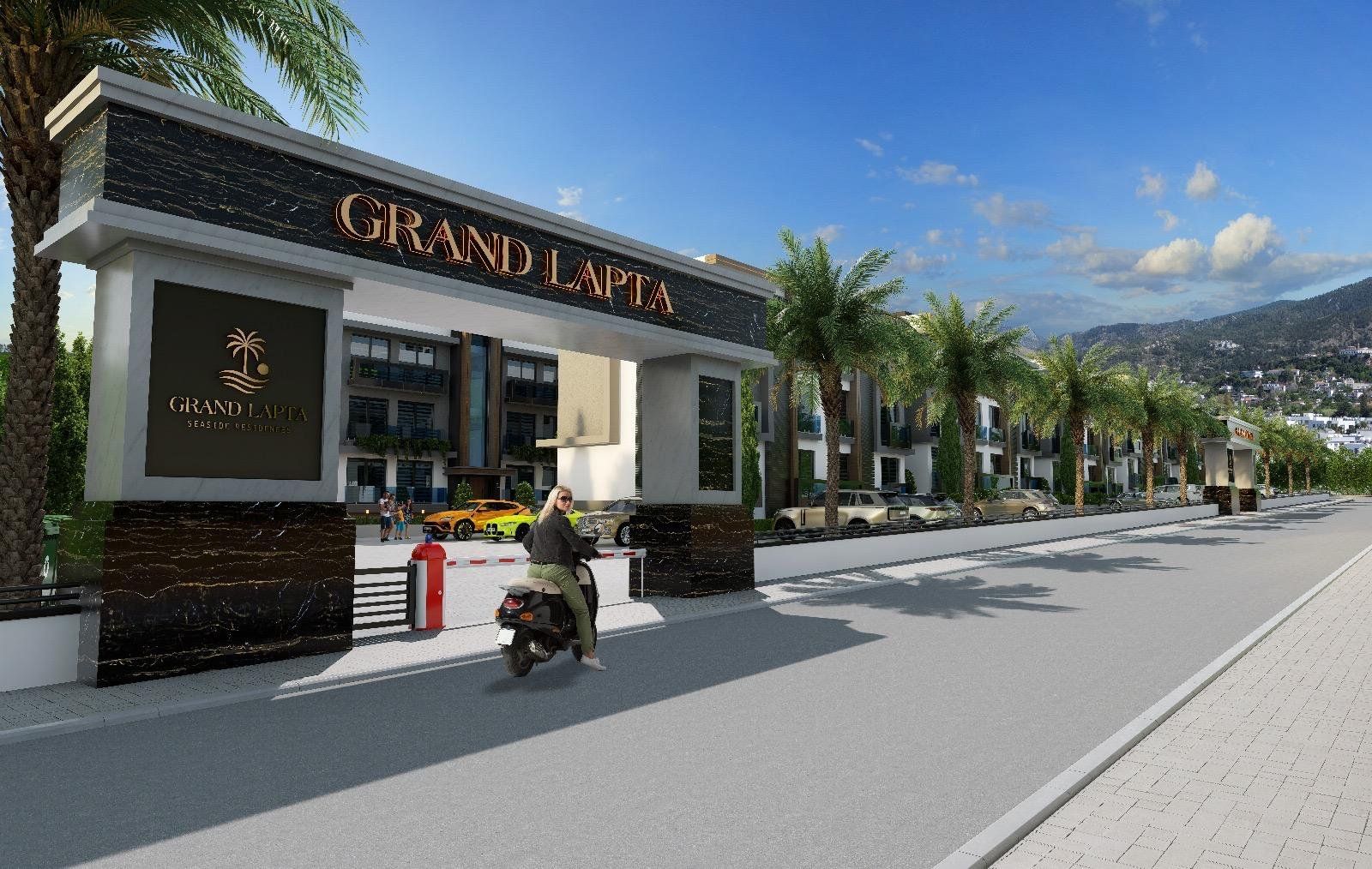 The gated entrance of Grand Lapta, with palm-lined drive and the Kyrenia mountains behind